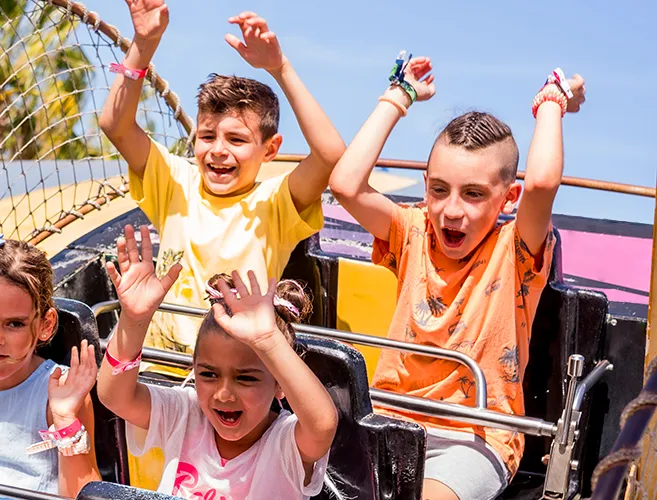 Niños celebrando con los brazos en alto en la atracción del barco pirata de Pola Park